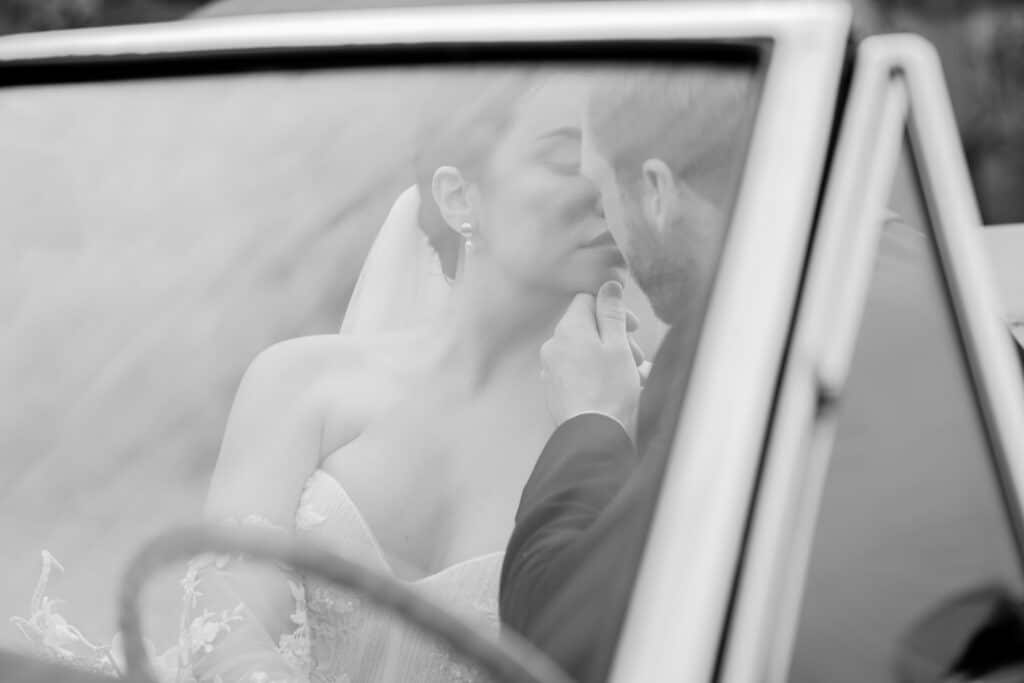 bride and groom sitting in red vintage wedding car outside manor house at euridge manor wedding