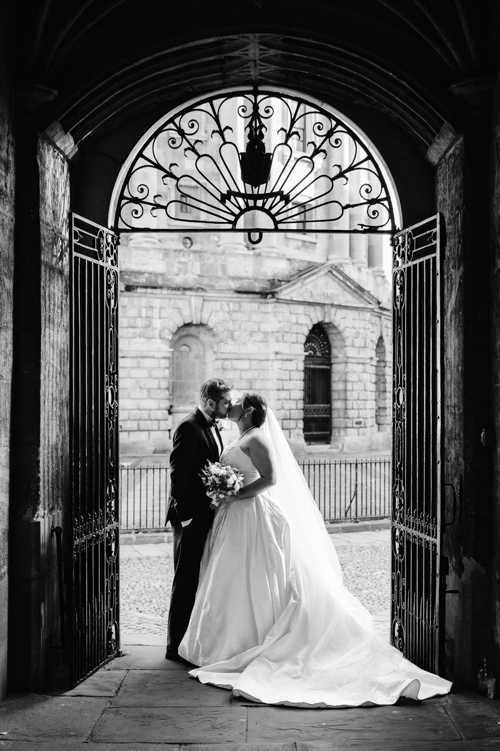 bride and groom kiss under archway overlooking the radcliffe camera oxford