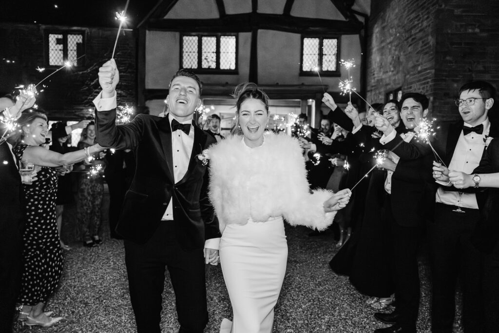 bride and groom walking in sparklers in front of lillibrooke manor