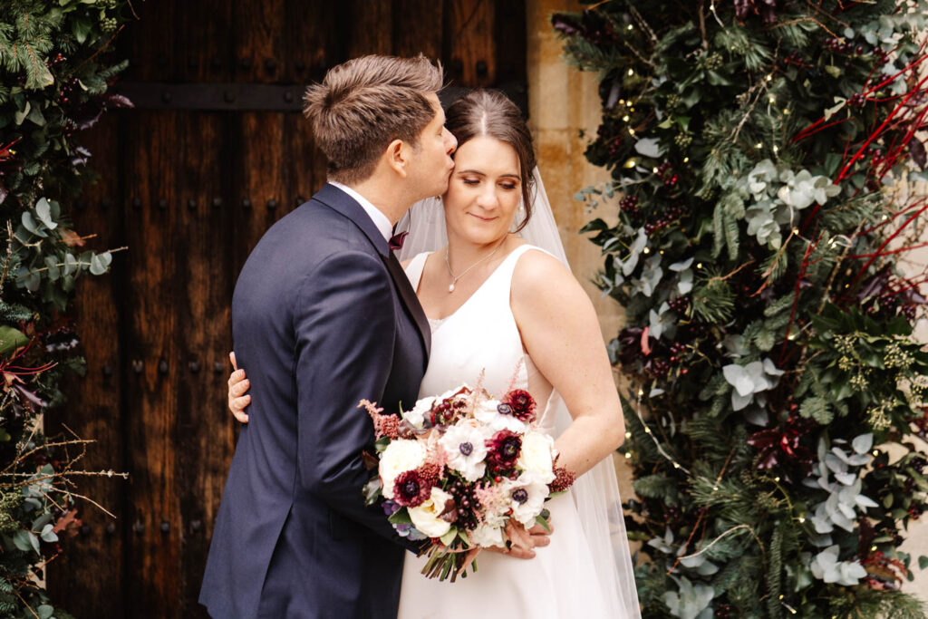 bride and groom portrait under christmas floral arch notley abbey